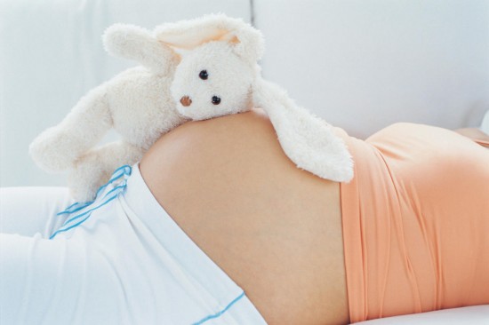 Stuffed rabbit on top of pregnant woman's belly